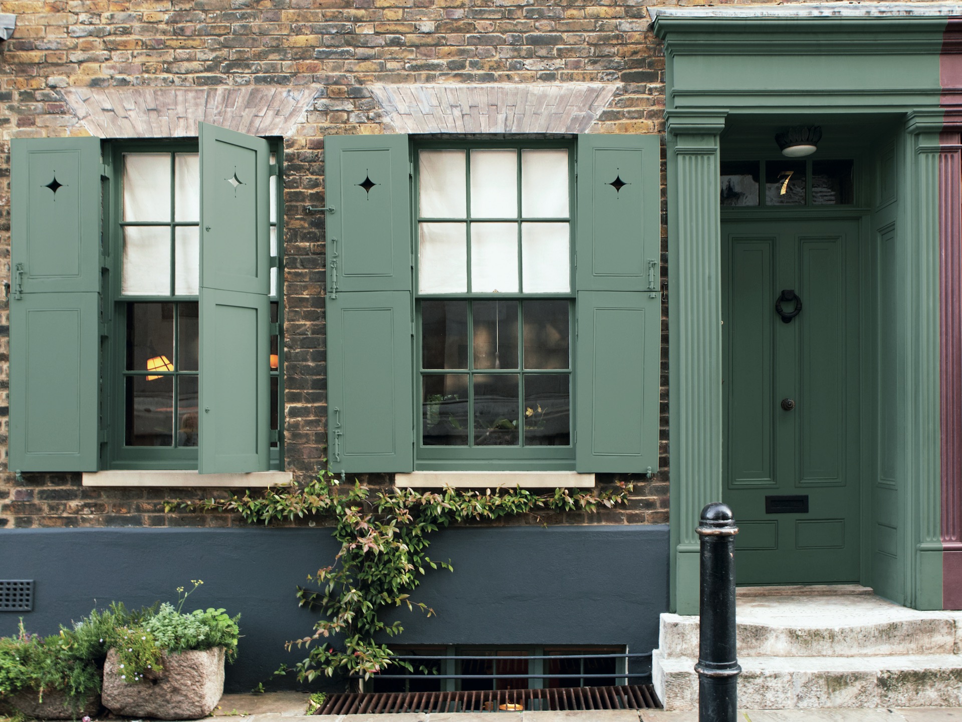 Front of house with shutters and front doors painted in green smoke by Farrow & Ball