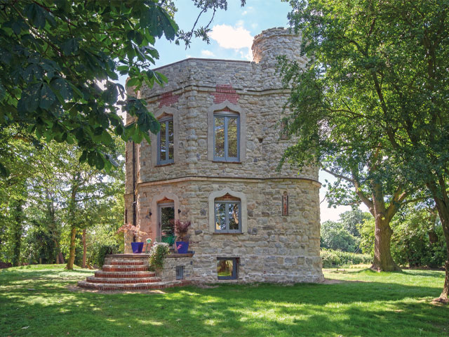 Stone Georgian folly circular steps grey windows. in open level field