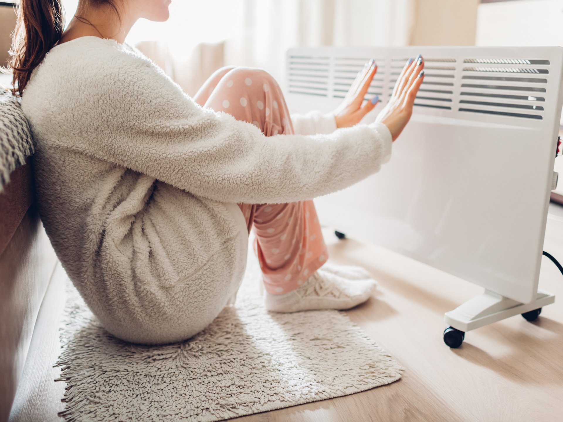 A person sat in front of an electric heater