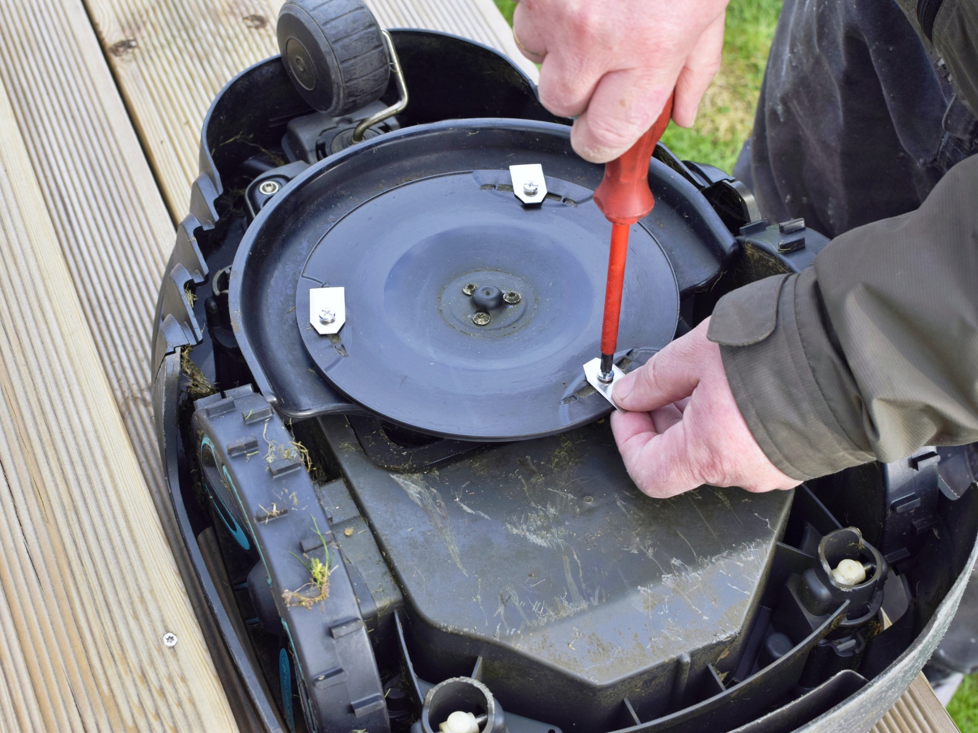 Man swaps blades for robotic lawn mower