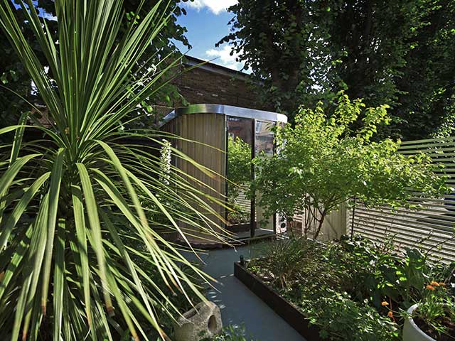 Prefab garden office with plants surrounding