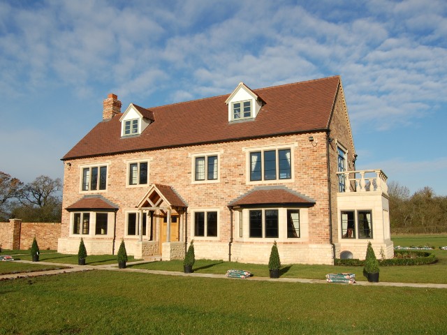 beautiful new brick house surrounded by open fields in the countryside