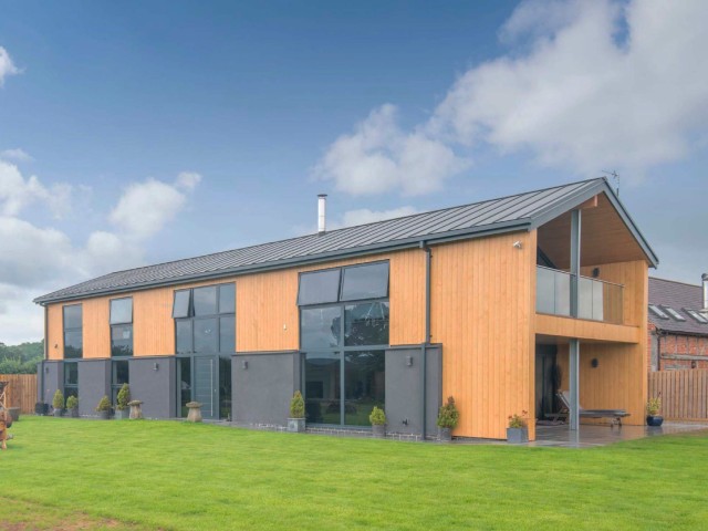 contemporary barn with double-height windows built behind an old farm house