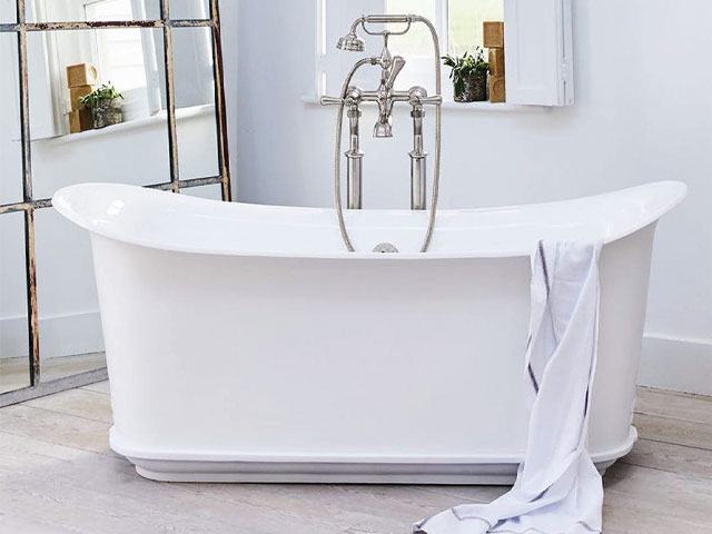 vintage bathroom. white cast iron freestanding bath silver taps and pipes freestanding tilted copper mirror