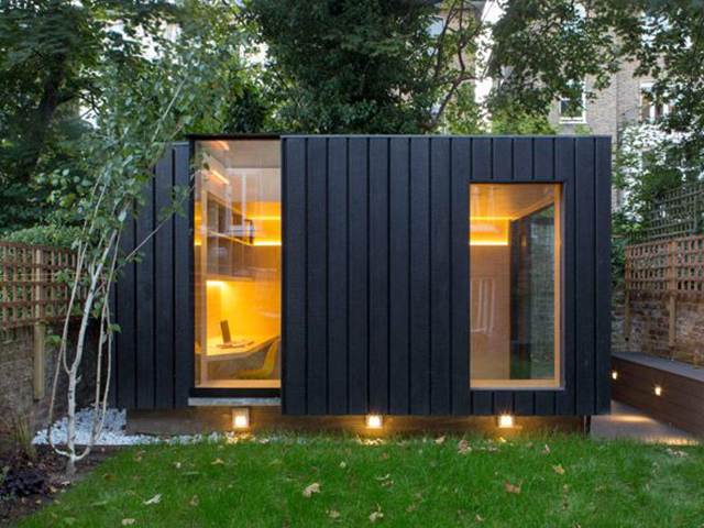 Dark timber boards clad a rectangular garden outbuilding