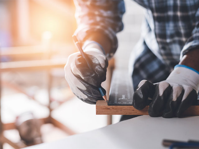 builder measuring a piece of wood on a building site