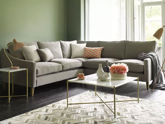 grey green settee in a green living room with marble coffee table and green walls 