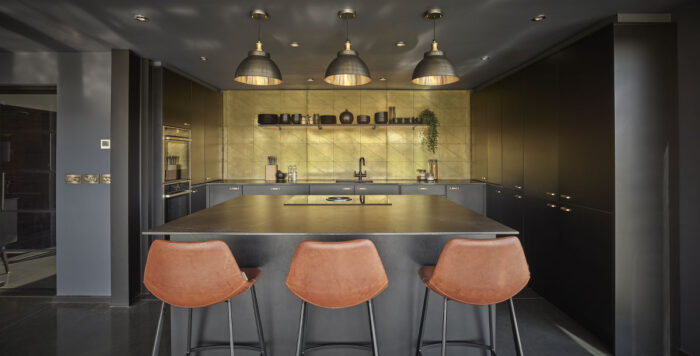 mixed metal industrial pendant lights in a black and gold kitchen