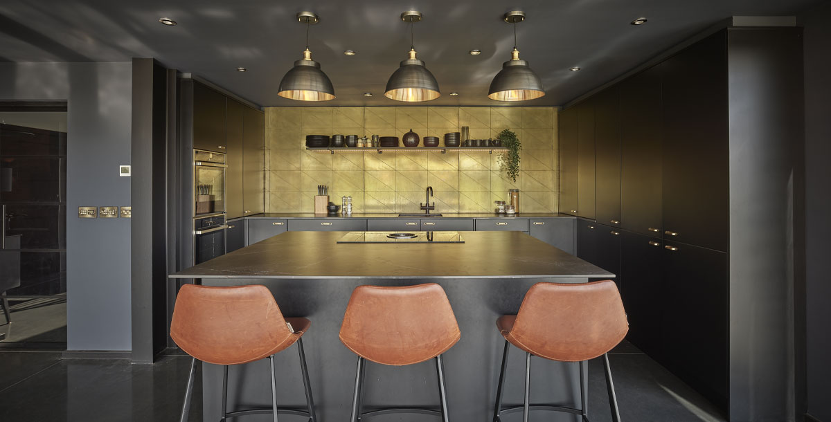 mixed metal industrial pendant lights in a black and gold kitchen