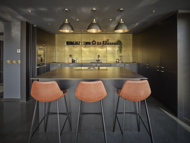 mixed metal industrial pendant lights in a black and gold kitchen