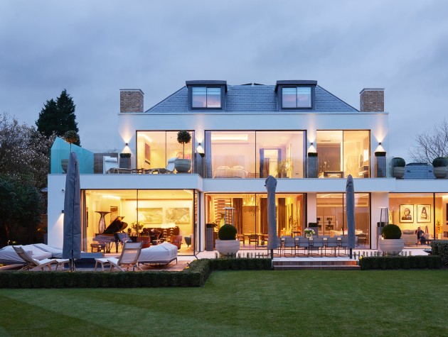 rear of modern home with large aluminium sliding doors lit up