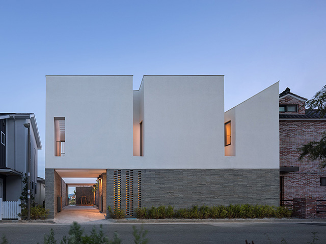 Exterior facade of a south Korean home with white rendered top half and horizontal brick below